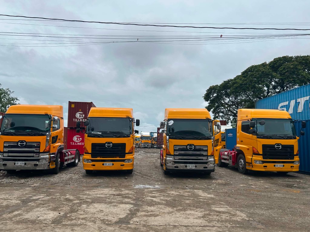 Yellow cargo trucks at a shipping container yard